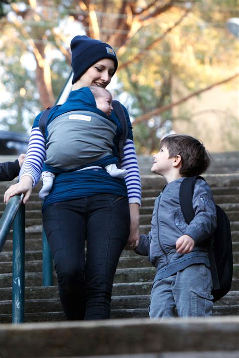 Anyuka babát tart a kezében hordozókendőben