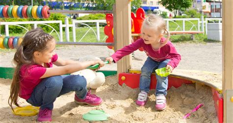 gyerekek játszanak egy árnyas, jól felszerelt bölcsődei udvaron