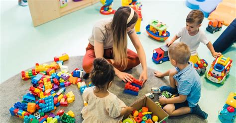 Gyermekekkel játszó bölcsődei gondozó